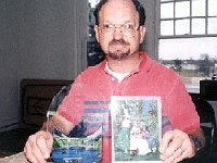 Chuck Edwards with a picture for one of his clocks in his right hand. Only the background is need for it to be completed.