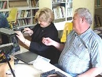 Carolyn Hollien works on her clock while husband Ron supervises.