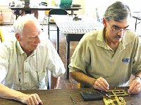 Dan Cole is installing a bushing using a hand bushing tool. Frank Desmond looks on.