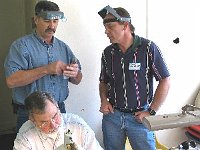 Joe Richards works with his lathe while assistant instructor Bill Andrle shows Bruce Woolridge how to hone his graver.