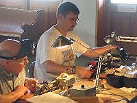 Tom Smith using his Unimat lathe cutting aluminum on a class project. John Acker using a Sherline lathe with his newly ground cutting tool.